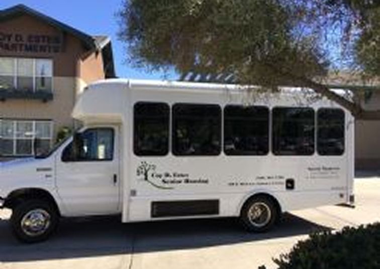 Coy D. Estes Senior Housing white shuttle bus parked outside the building, offering resident transportation services.